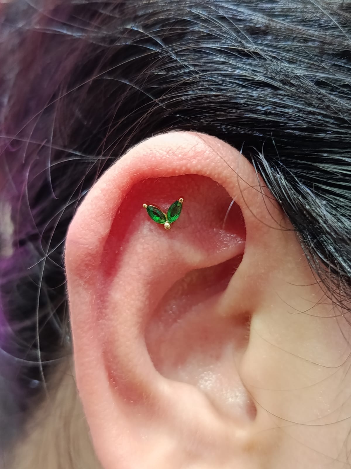 Conch piercing with green gem leaves